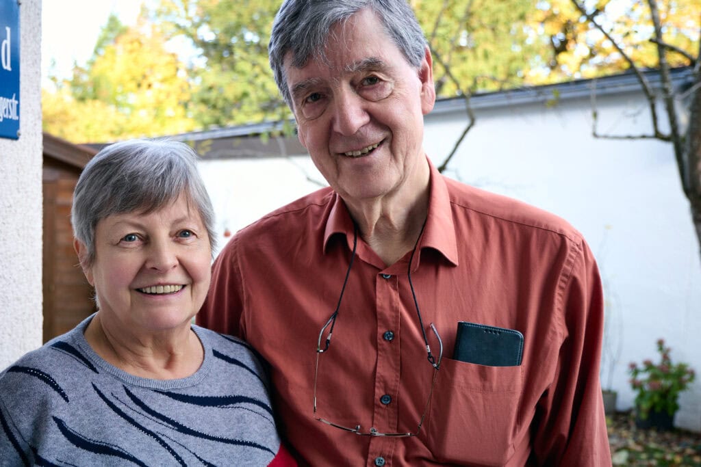 Wandbild mit älteren Paar, lachend im Garten, Natur im Hintergrund, gemütliche Atmosphäre, Senioren, Glück, Gemeinschaft.