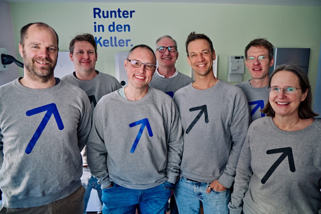 Gruppe von Mitarbeitern in Sonnwärts-Shirts im Büro, lächelnd und motiviert.