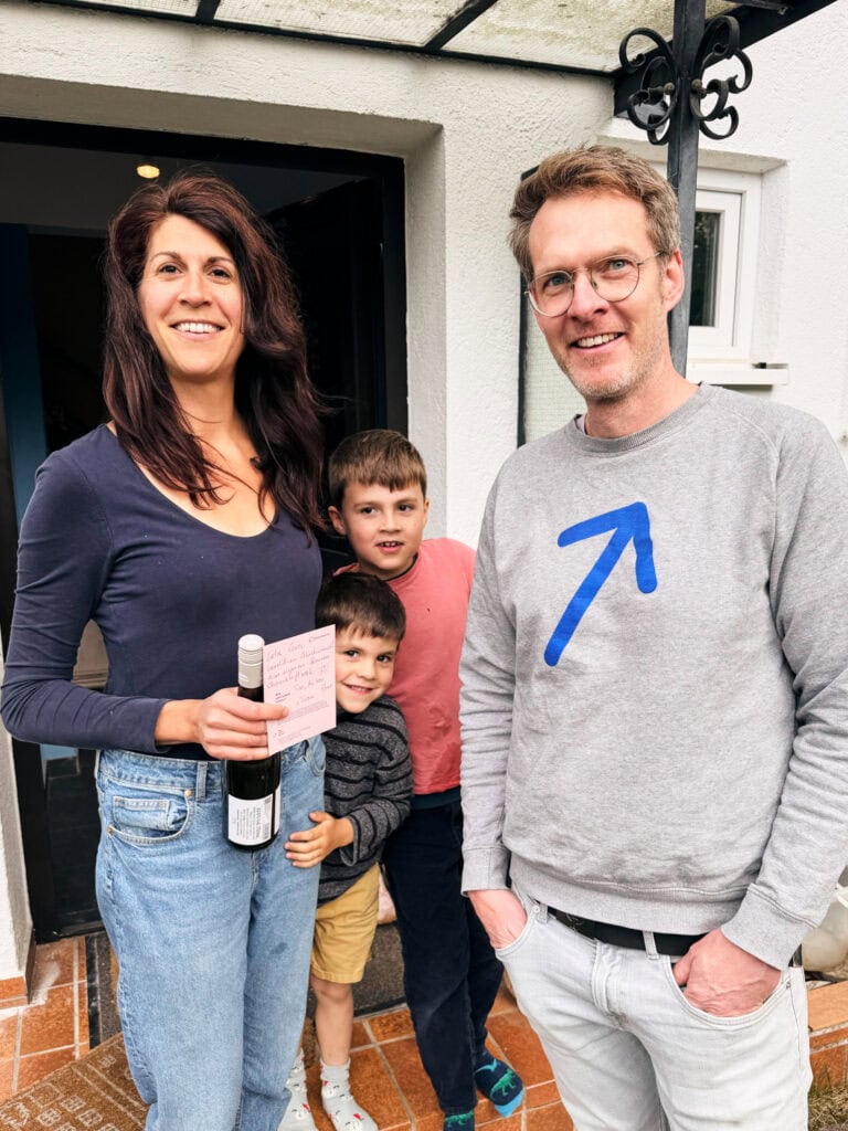 Familie vor Haus mit Solaranlage, nachhaltige Energie, Sonnwärts.