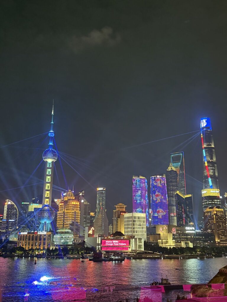 Nachtaufnahme der Skyline von Shanghai mit leuchtenden Gebäuden und Lichtern.